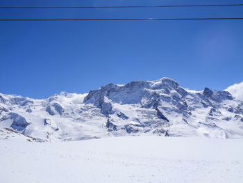 Scenic view of snowcapped mountains against clear blue sky