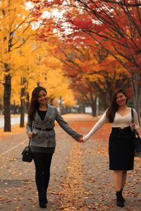 Full length portrait of a smiling young woman during autumn