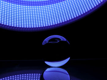 Close-up of illuminated lighting equipment on table against black background