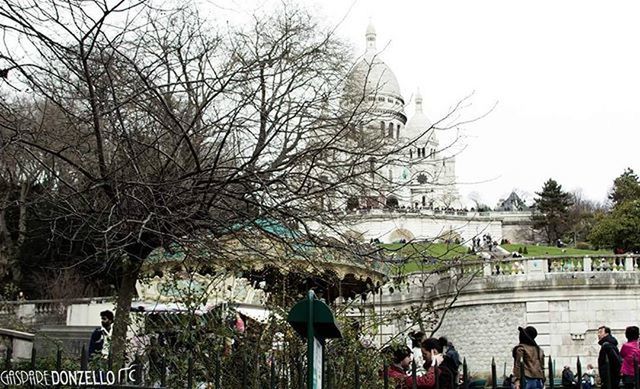 tree, architecture, large group of people, built structure, building exterior, person, lifestyles, men, clear sky, water, leisure activity, mixed age range, city, bare tree, tourist, travel destinations, tourism, river, city life