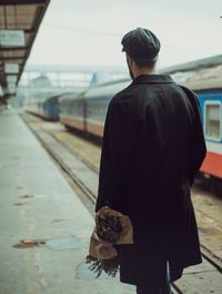 Rear view of man standing at railroad station platform
