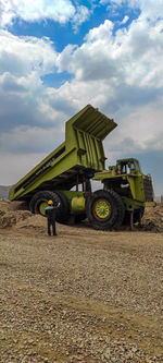 Man by tractor on field against sky