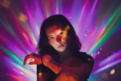 Portrait of young woman against illuminated lights