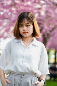 Portrait of a beautiful young woman standing against red wall