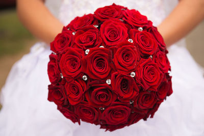 Close-up of hands holding red rose bouquet