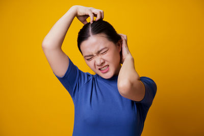 Portrait of young woman against yellow background