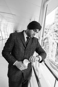 Man holding camera while standing against window