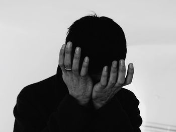 Close-up of depressed man against white wall