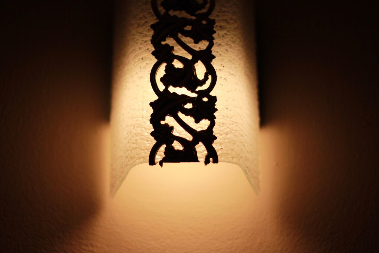 CLOSE-UP OF ILLUMINATED LAMP HANGING AGAINST WALL