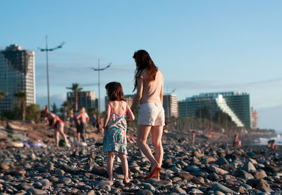 Rear view of women standing on footpath against sky