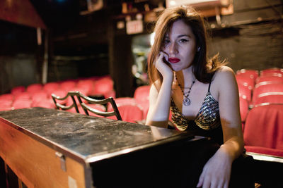 Portrait of young woman sitting on table at restaurant