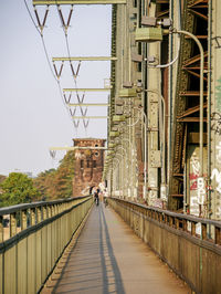 Men riding bicycles on footbridge against sky in city