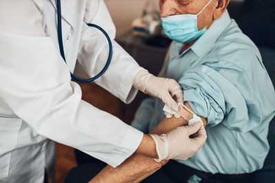 Doctor putting a plaster in place of injection of vaccine to senior man patient. vaccination