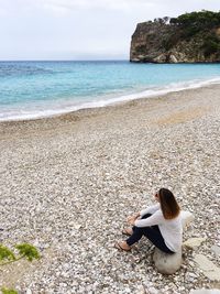 High angle view of woman sitting on rock at beach