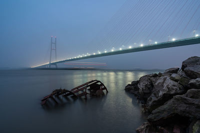 Suspension bridge over river against sky