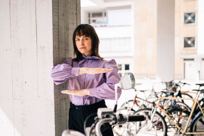 Portrait of woman with bicycle standing against wall