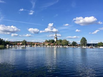 View of buildings by river against cloudy sky