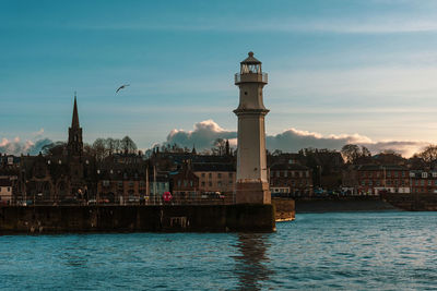 View of buildings by sea against sky in city