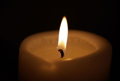 Close-up of illuminated candle against black background