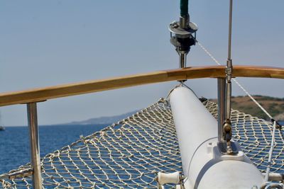 Close-up of sailboat sailing on sea against clear sky