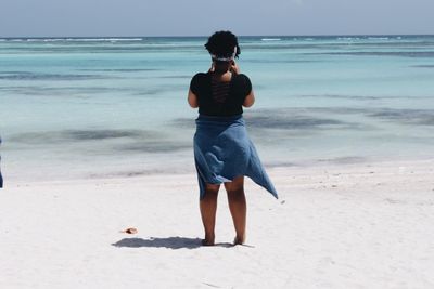 Rear view of young woman standing on beach
