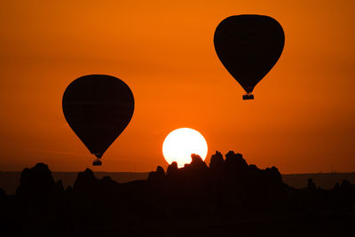 Silhouette hot air balloons against clear orange sky
