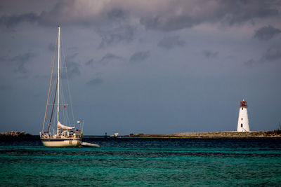 Boat sailing on sea with lighthouse in background against sky