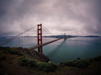 View of suspension bridge against cloudy sky