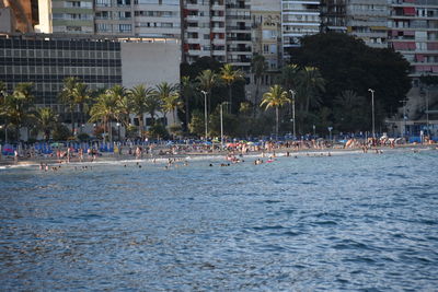 Group of people on beach by buildings in city
