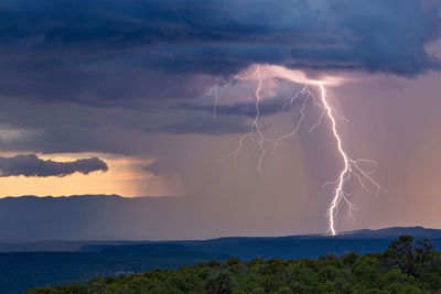 Lightning over landscape against sky at night