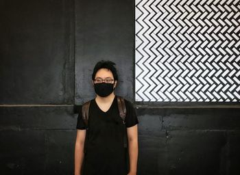 Portrait of young man standing against wall