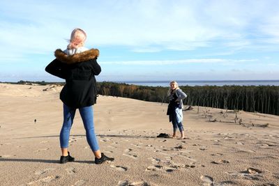 Full length of friends at beach against sky