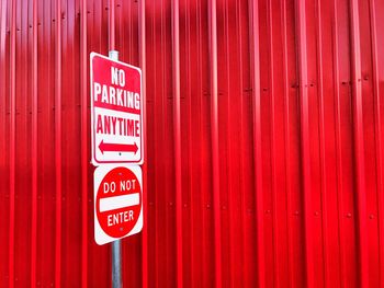 Close-up of no parking sign on red wall