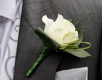 Close up of cream rose button hole for groom in wedding day