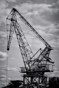 Low angle view of crane against cloudy sky