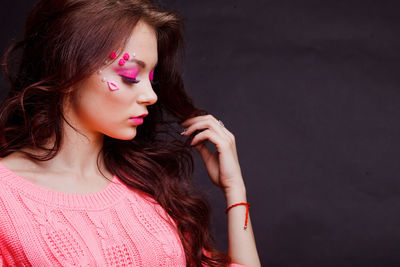 Close-up of beautiful young woman with make-up against gray background