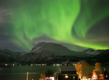 Scenic view of lake by mountains against sky at night