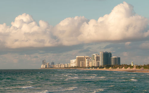 Sea by buildings against sky in city