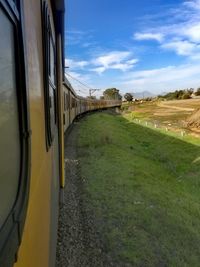 Train amidst grass against sky