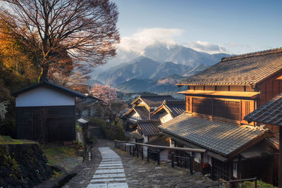 Houses amidst trees and buildings against sky during winter