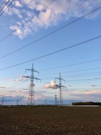 Low angle view of electricity pylon on field against sky