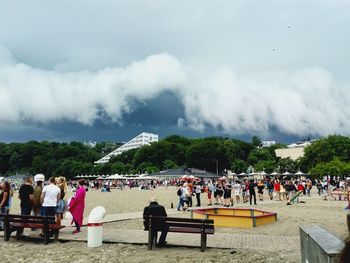 People at playground against cloudy sky