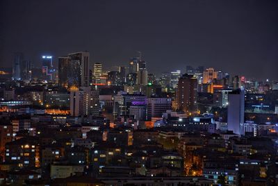 Illuminated cityscape against sky at night