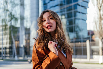 Portrait of smiling young woman in coat looking away outdoors. girl in city