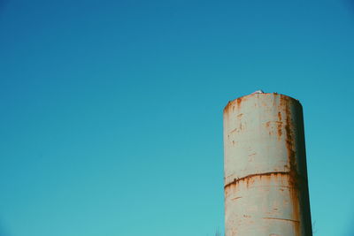 Low angle view of old chimney against clear blue sky