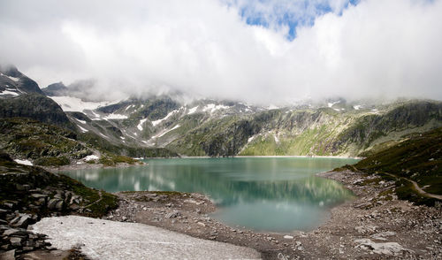 Scenic view of mountains and lake against cloudy sky