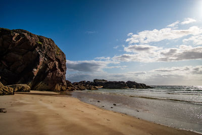 Rock formations on beach against sky