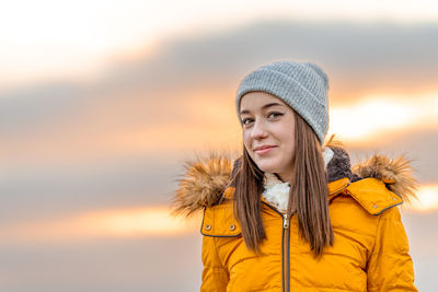 Portrait of young woman standing against sky during sunset