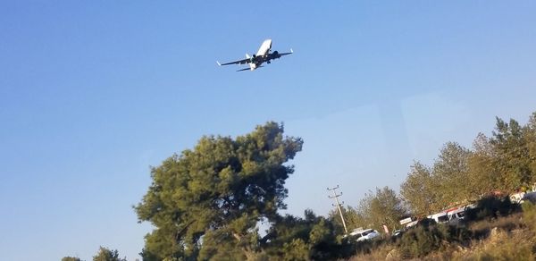 Low angle view of airplane flying against clear blue sky