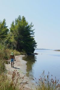 Rear view of men by lake against sky